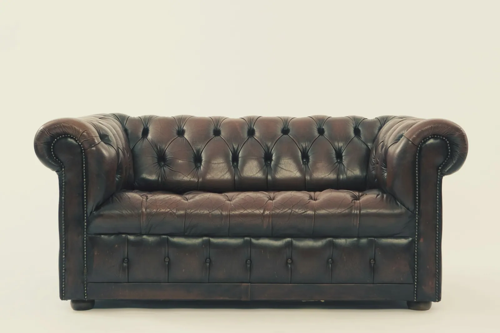 Sofa Chesterfield kulit cokelat tua dengan kancing tarik