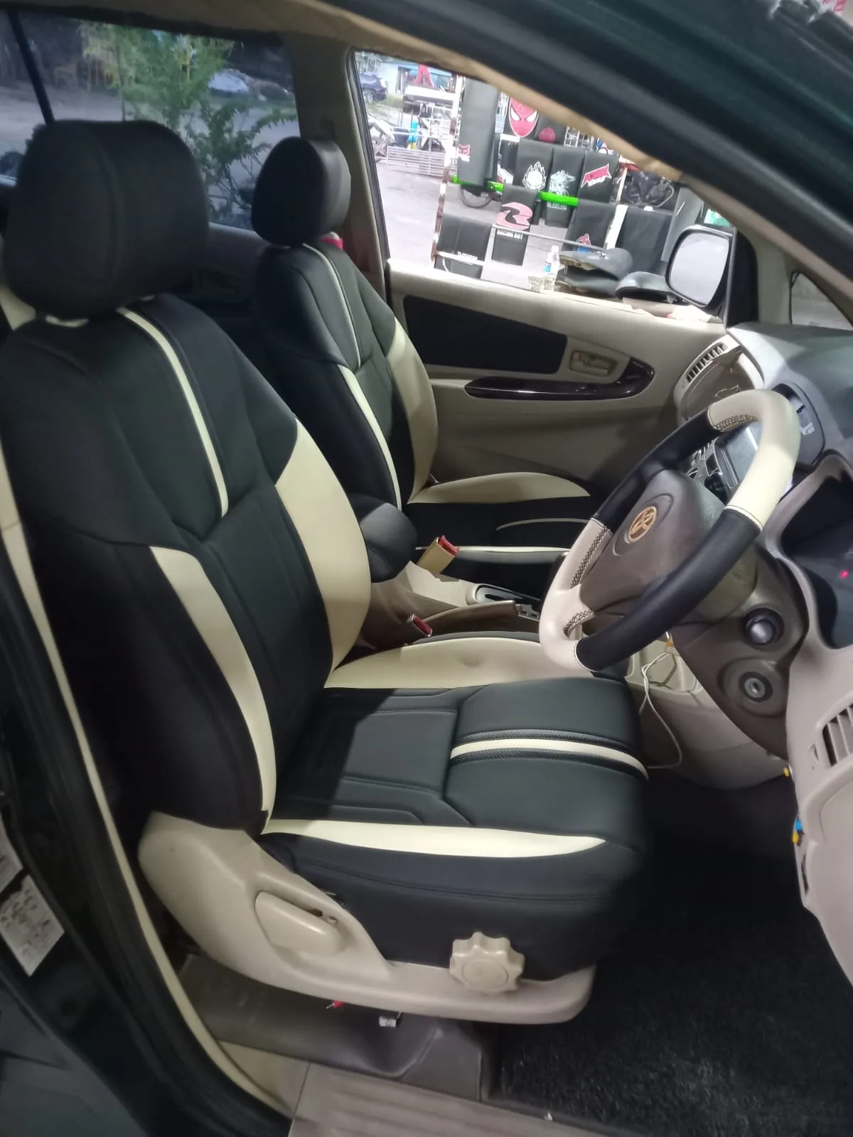 Jok depan mobil hitam dengan panel krem dan garis putih, terpasang di kabin