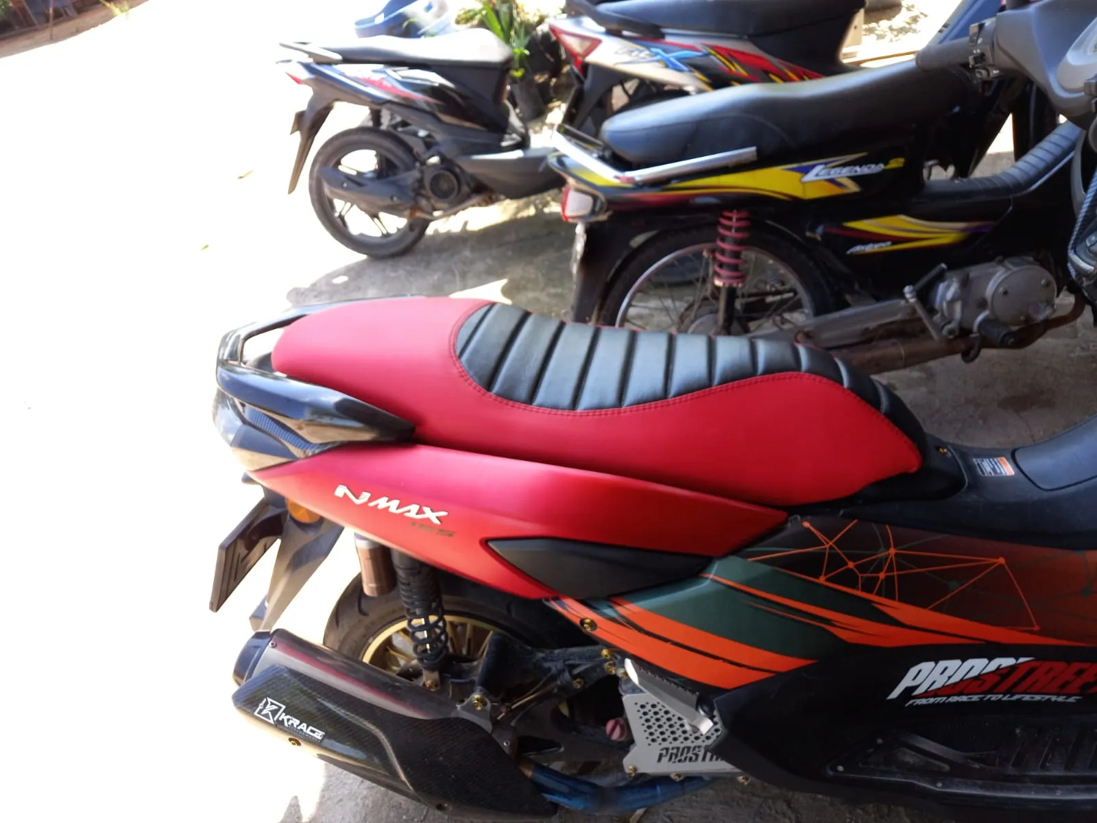 Jok skuter matik merah dengan bagian bergaris hitam